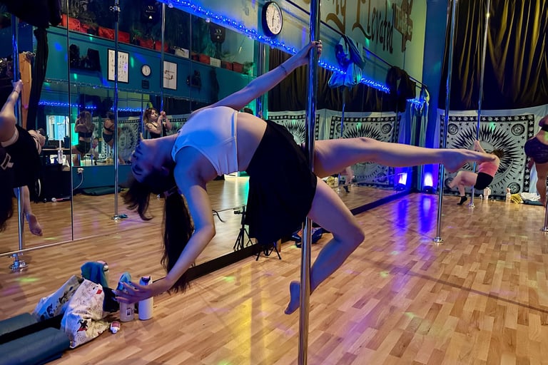 Side view of Ryanne hitting a leaned back pose on a pole at a dance studio.