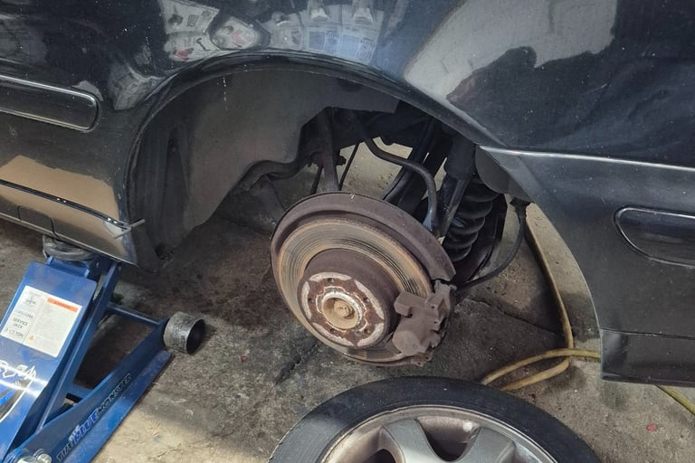 wheel has been removed to reveal old brakes and rotors that need to be replaced