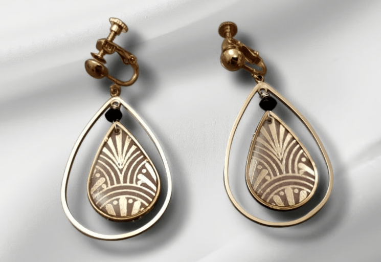 Vintage gold screw-back clip-on earrings with Art Deco teardrop patterns on white silk.