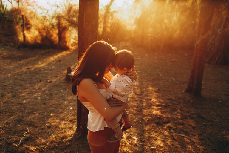 Mamà abrazando a su hijo pequeño en medio del bosque