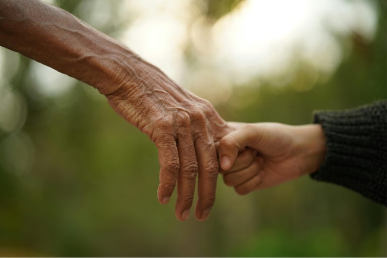 Mano de adulto mayor sosteniendo la mano de alguien más joven