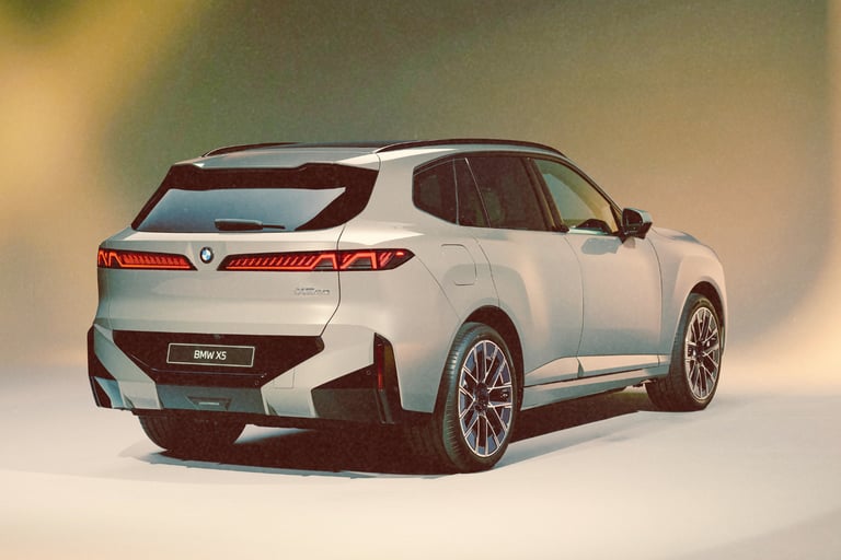 Rear three-quarter view of a silver BMW X5 luxury SUV in a studio with bright lighting.