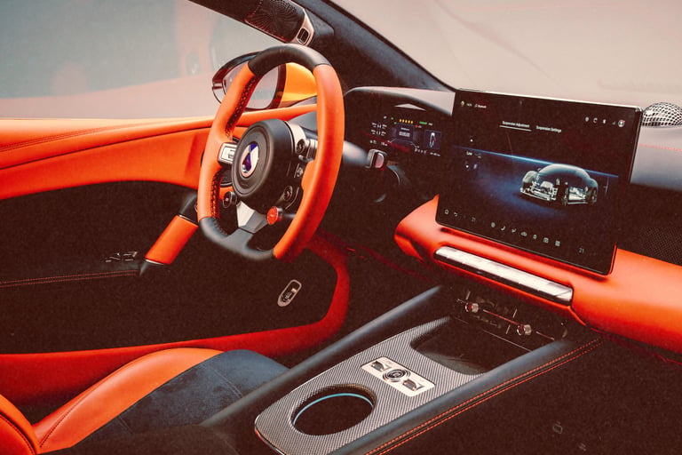 Luxury sports car interior featuring orange leather upholstery, carbon fiber trim, and a digital infotainment screen.
