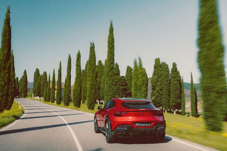 A red Ferrari Purosangue SUV driving on a scenic road lined with tall cypress trees in Tuscany.