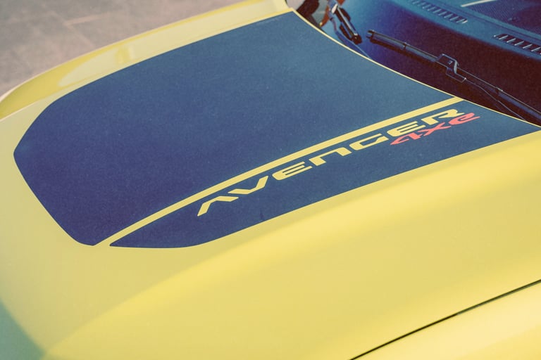 A close-up of a yellow Jeep Avenger 4xe hood featuring a matte black anti-glare decal.