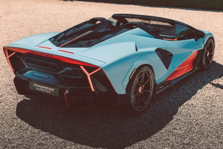 A light blue and orange Fenomeno Roadster luxury sports car parked on a gravel surface.