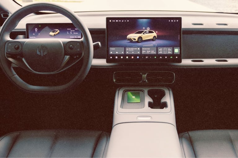 Modern electric vehicle interior featuring a digital cockpit, steering wheel, and large infotainment touchscreen display.