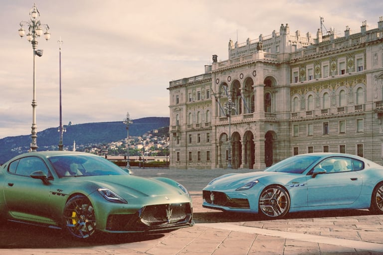 Two Maserati GranTurismo luxury sports cars parked in a historic European plaza near a grand building.