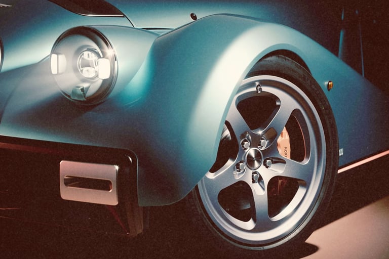 Close-up of a blue Morgan Supersport luxury sports car with glowing LED headlights and alloy wheels.