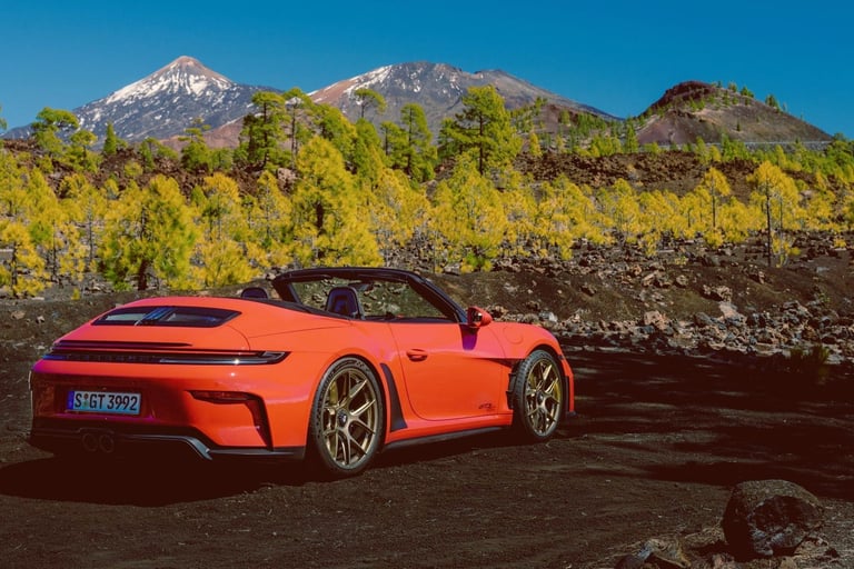 Red Porsche 911 GT3 S/C parked on a volcanic landscape with mountains in the background.
