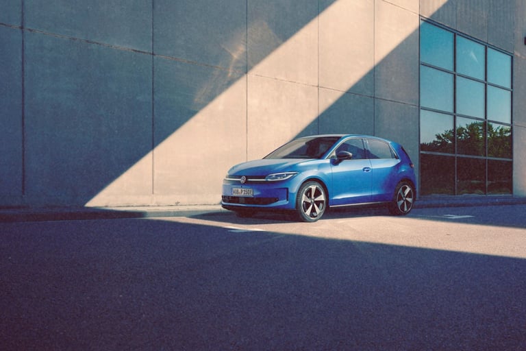 A blue Volkswagen ID. Polo parked in front of a modern concrete building with sunlight and shadows.