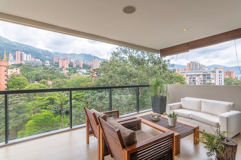 Modern luxury apartment balcony with wooden patio furniture and a scenic mountain city view.
