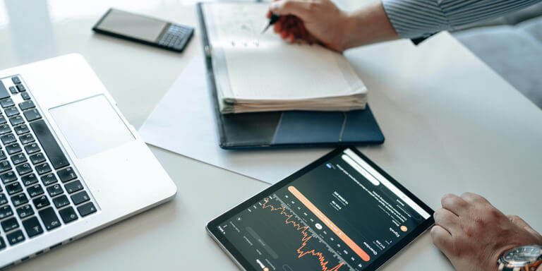 Consultant executing strategy with laptop, tablet, and notes during project planning