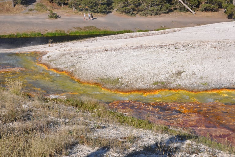 a stream of water with a person walking on it and geothermal activity