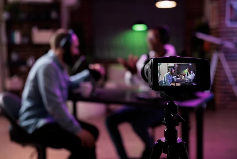 Video camera recording two guests talking on a podcast set at Miami Creator Studio.
