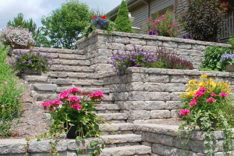 Landscaped block retaining wall with stone steps and plants