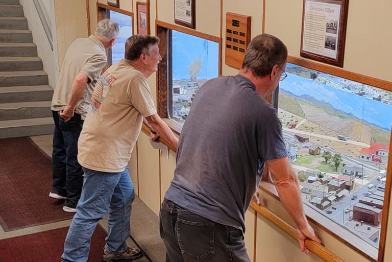 Viewing gallery windows with vistors looking at the model train layout