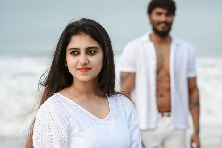 Save the date photoshoot in which bride and groom posing in white costumes on a beach in Kerala