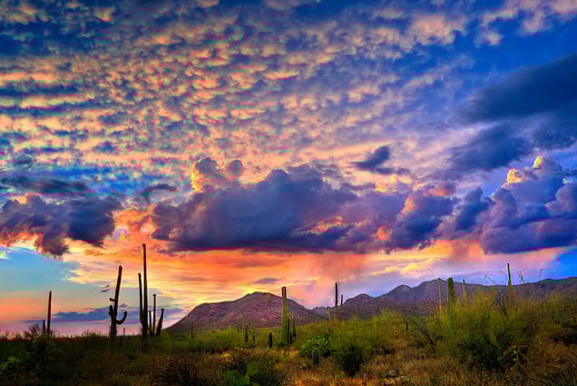 a sunset sky with clouds and mountains in the background