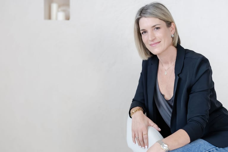 Yvonne seated in a therapy office, neutral background, relaxed portrait.