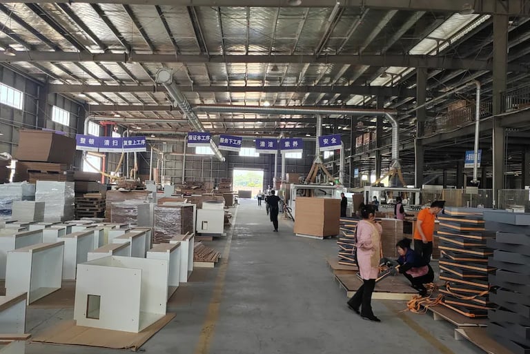 Workers assembling furniture in a large industrial woodworking factory warehouse.