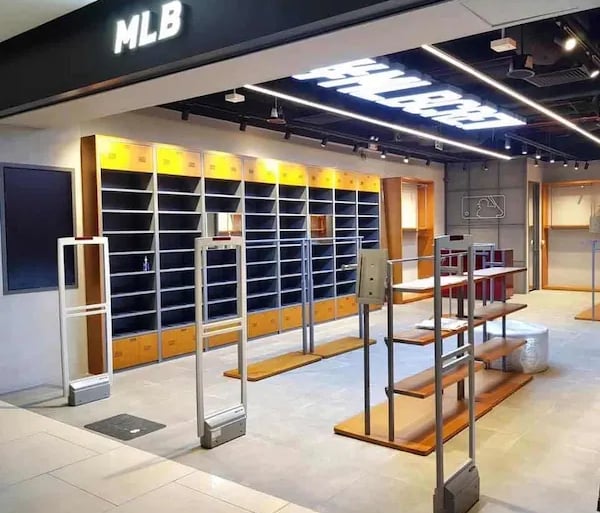 Interior of an empty MLB retail store featuring industrial display shelves and security gates.