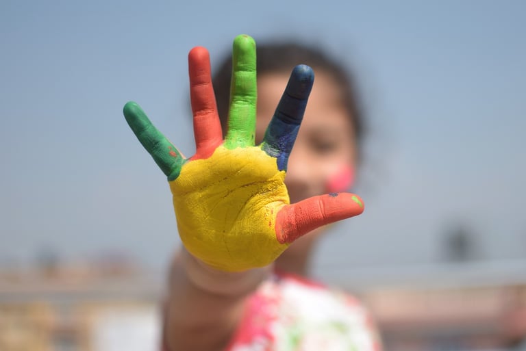 Child’s hand covered in colorful paint.