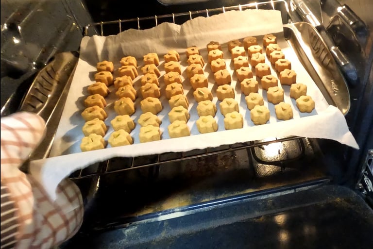 Small shaped cookies on a parchment-lined tray being placed into the oven