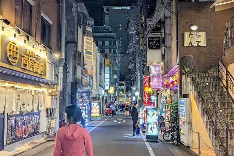 Traveler walking through a lively street at night in Shizuoka, Japan.