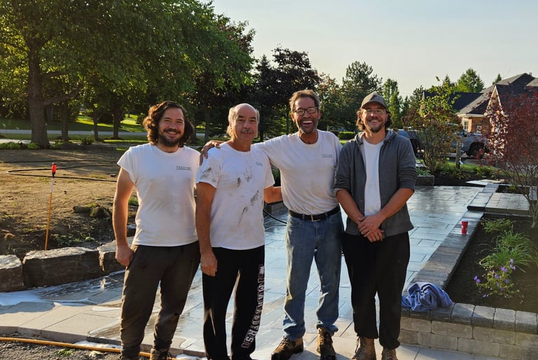 Professional landscaping crew standing on a newly installed stone patio in a residential backyard.