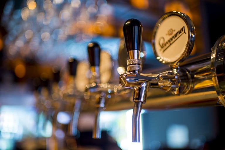 a row of beer taps with a beer on a bar