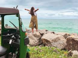 a woman standing on a rock wall with her arms outstretched out