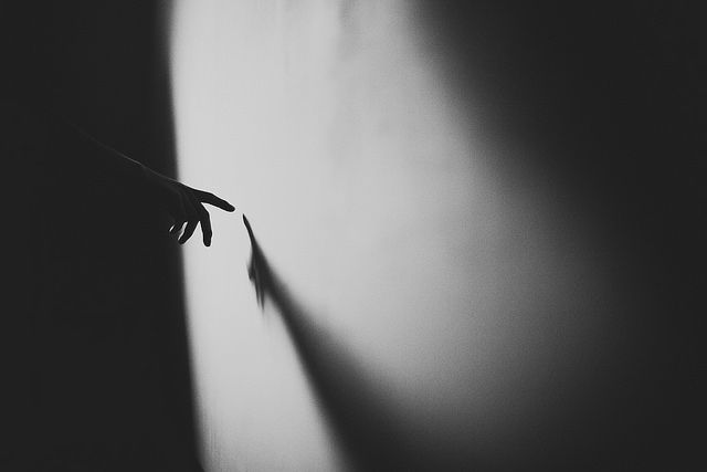 black and white photo hand on wall casting shadow