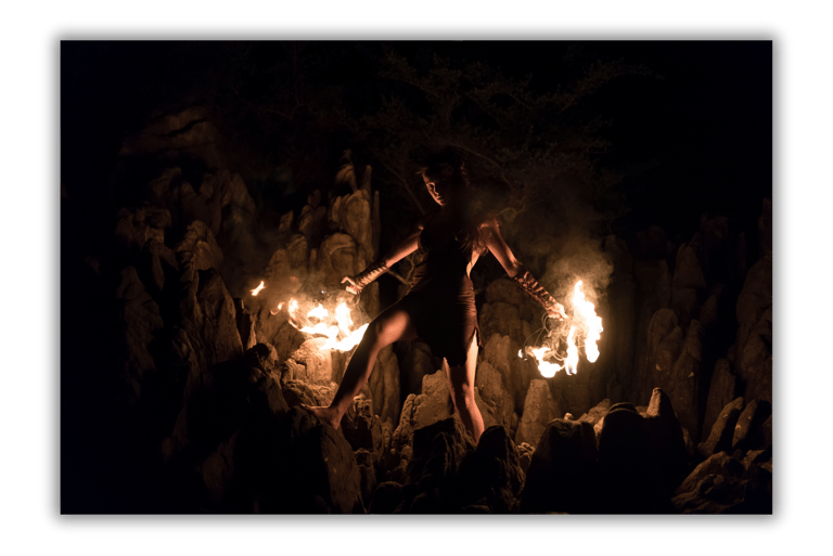 a woman in a black dress is holding a fire