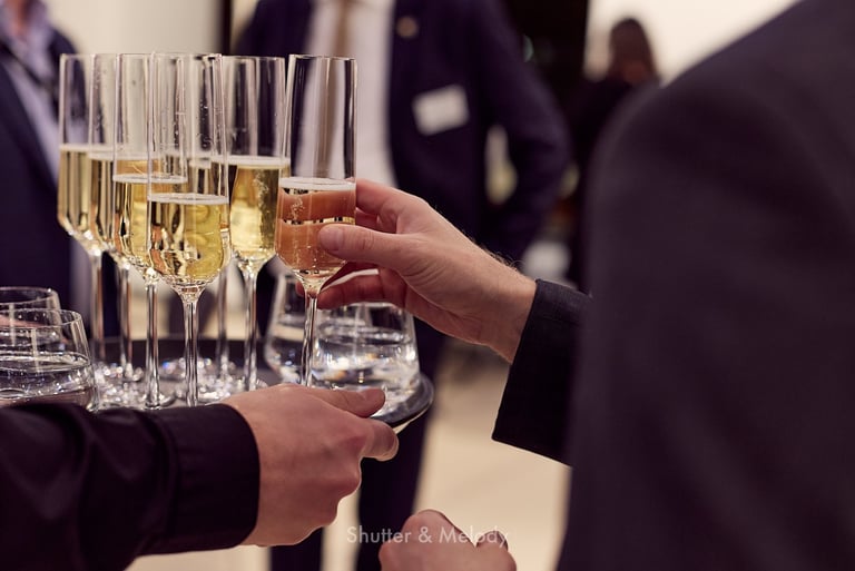 Ein Gast nimmt ein Glas Sekt von einem Tablett in die Hand.