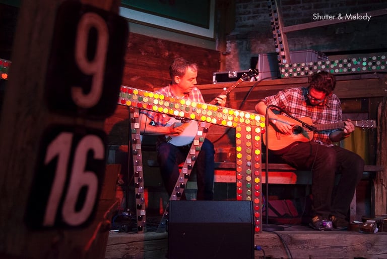 Ein Mann spielt Banjo und ein anderer Gitarre auf der Bühne im Kater.