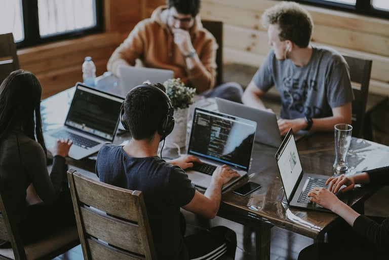 A group of people sitting around a table with laptops, discussing brand confusion and strategy.