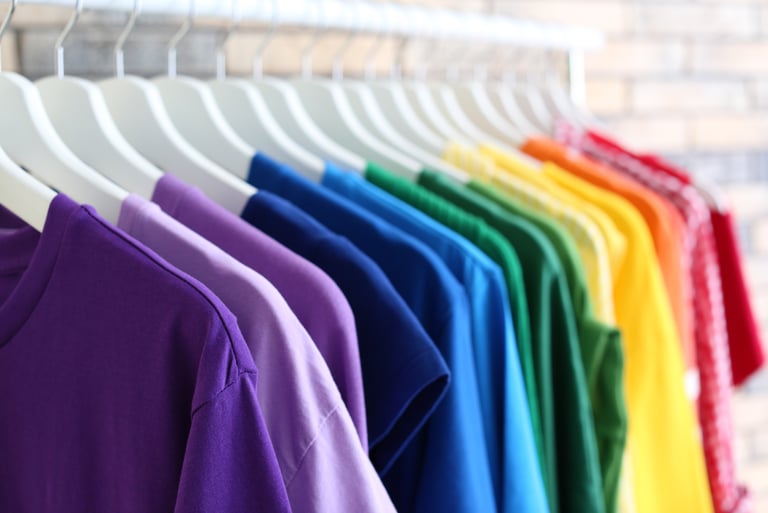 Foto de camisetas colgadas en perchas y ordenadas por el color del arcoiris