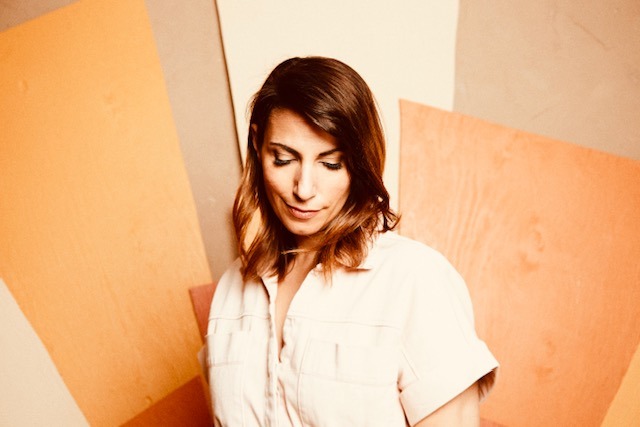 a woman in a white shirt and jeans standing in front of a wall