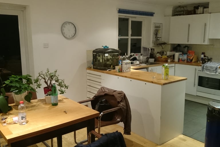 Una cucina con tante cose sul ripiano e un tavolo con dei fiori sopra