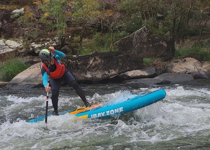 Una chica remando sobre un rápido del río ulla