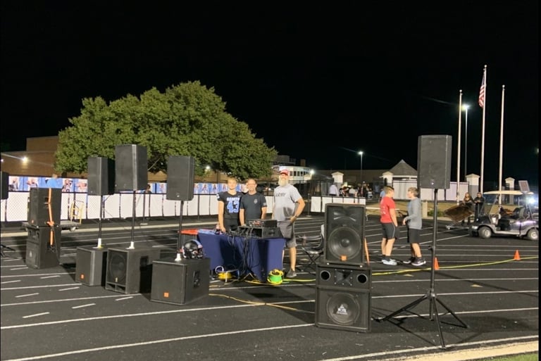 speakers and 5 men standing on a high school track