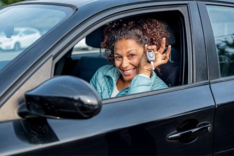 a woman in a car holding up her keys