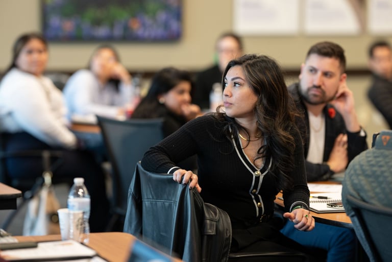 Jenny turns toward the speaker as Arnaldo listens behind her during Hispanic Austin Leadership class