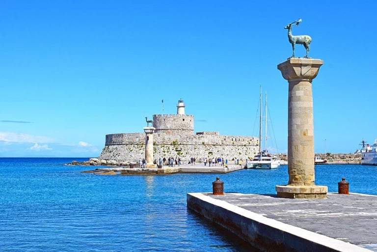 Mandraki Harbor in Rhodes Greece featuring deer statues and the Fort of Saint Nicholas.