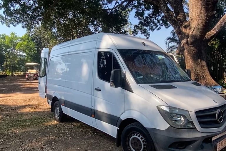a van parked in a field with a tree in the background