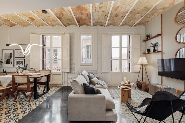 Modern living room featuring exposed brick walls, hydraulic tile floors, and Catalan vaulted ceiling