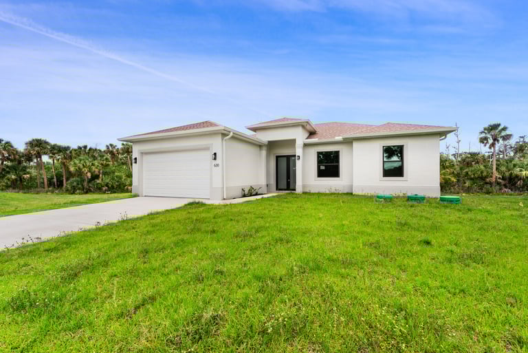 Single-family new construction home with landscaped front yard in Lee County, Florida.
