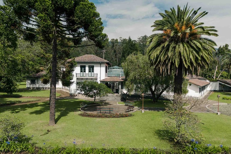 Fotografía con dron de mansión colonial de paredes blancas con techo naranja, cúpulas rodeada de naturaleza Quito Ecuador