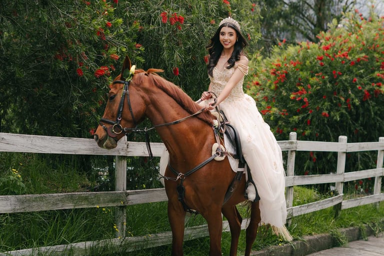 Fotografía de quinceañera con vestido amarillo montada a caballo en un lugar con vallas, flores rojas de Quito Ecuador